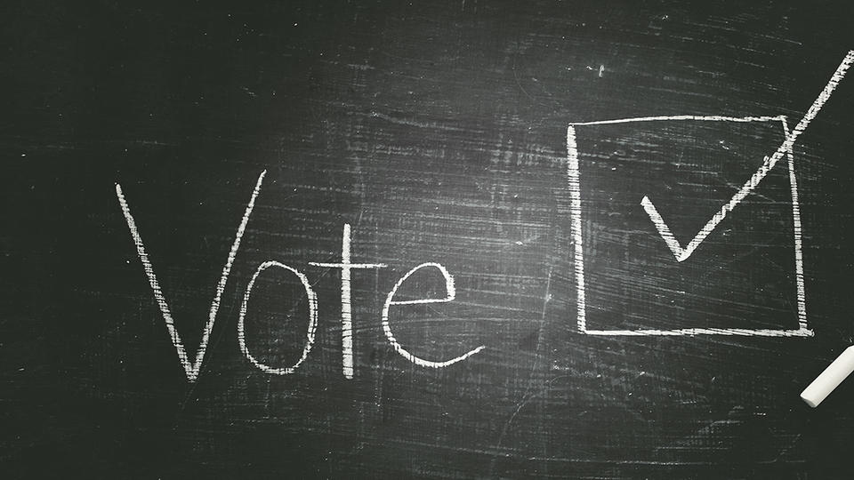 Chalk board that reads "Vote" with a checked box next to it. 