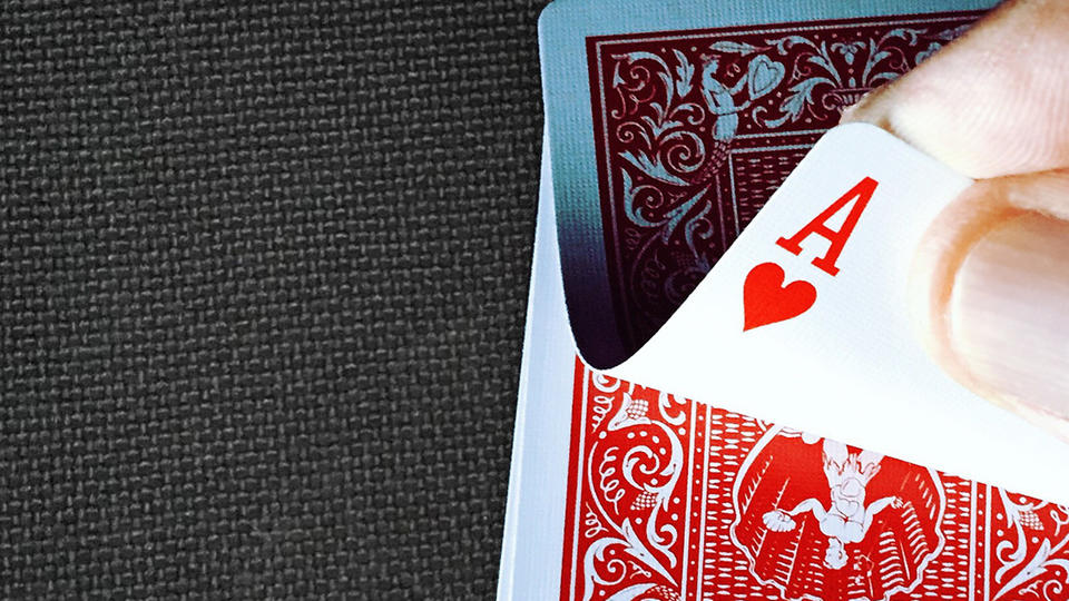 Flipping over a playing card to reveal the ace of hearts 