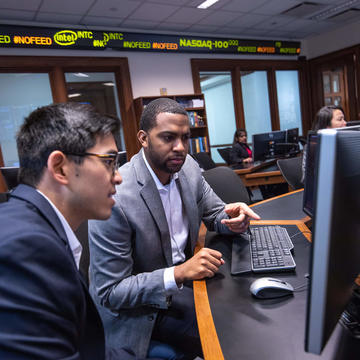 Two students in the Finance Center looking at a monitor