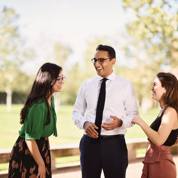 Two female students speaking to male professor outdoors