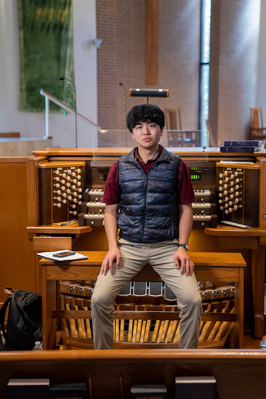 Bruce Xu sits in front of a pipe organ