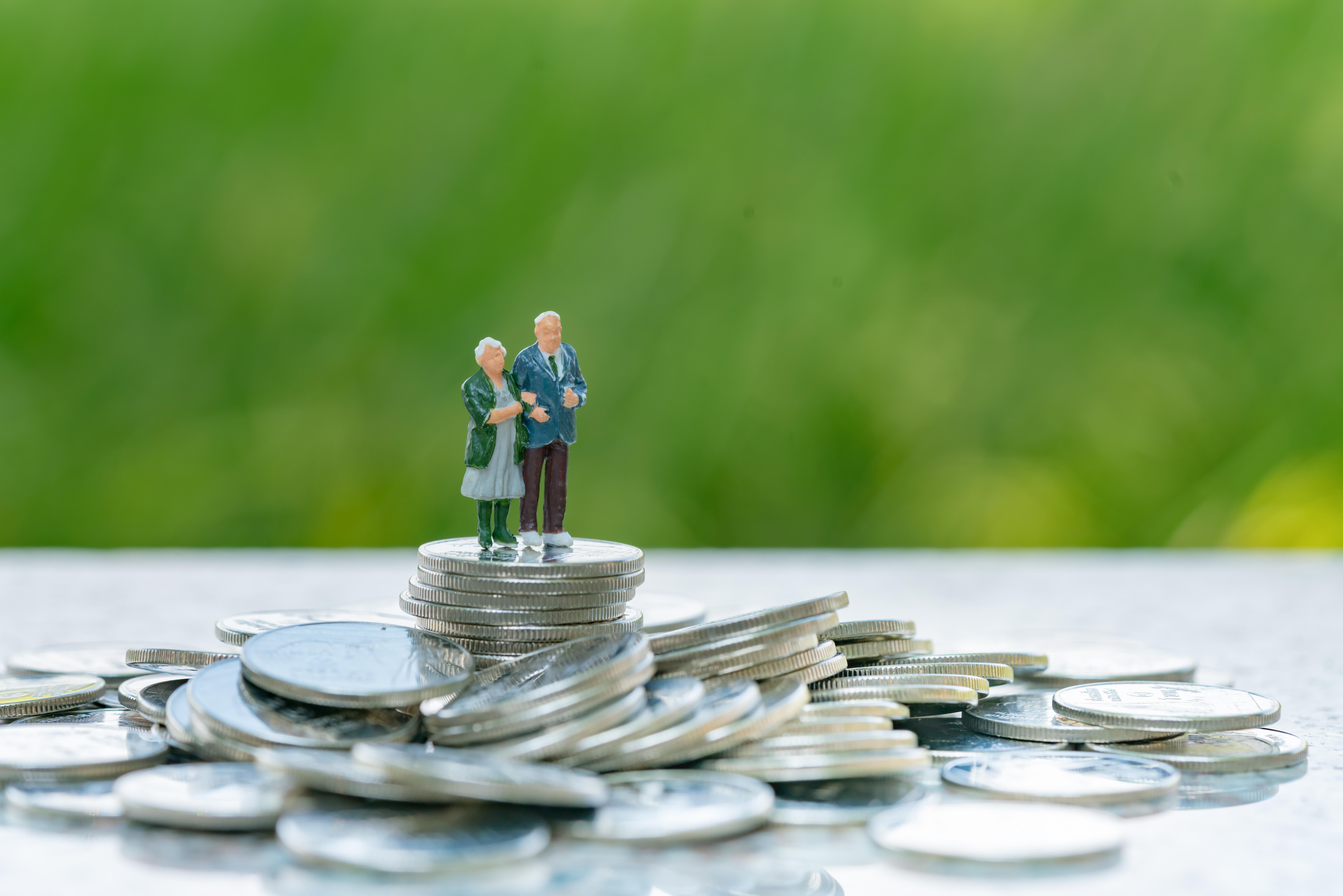 Older couple figurine standing on pile of coins