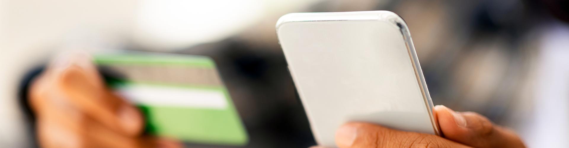 Person holding credit card and phone