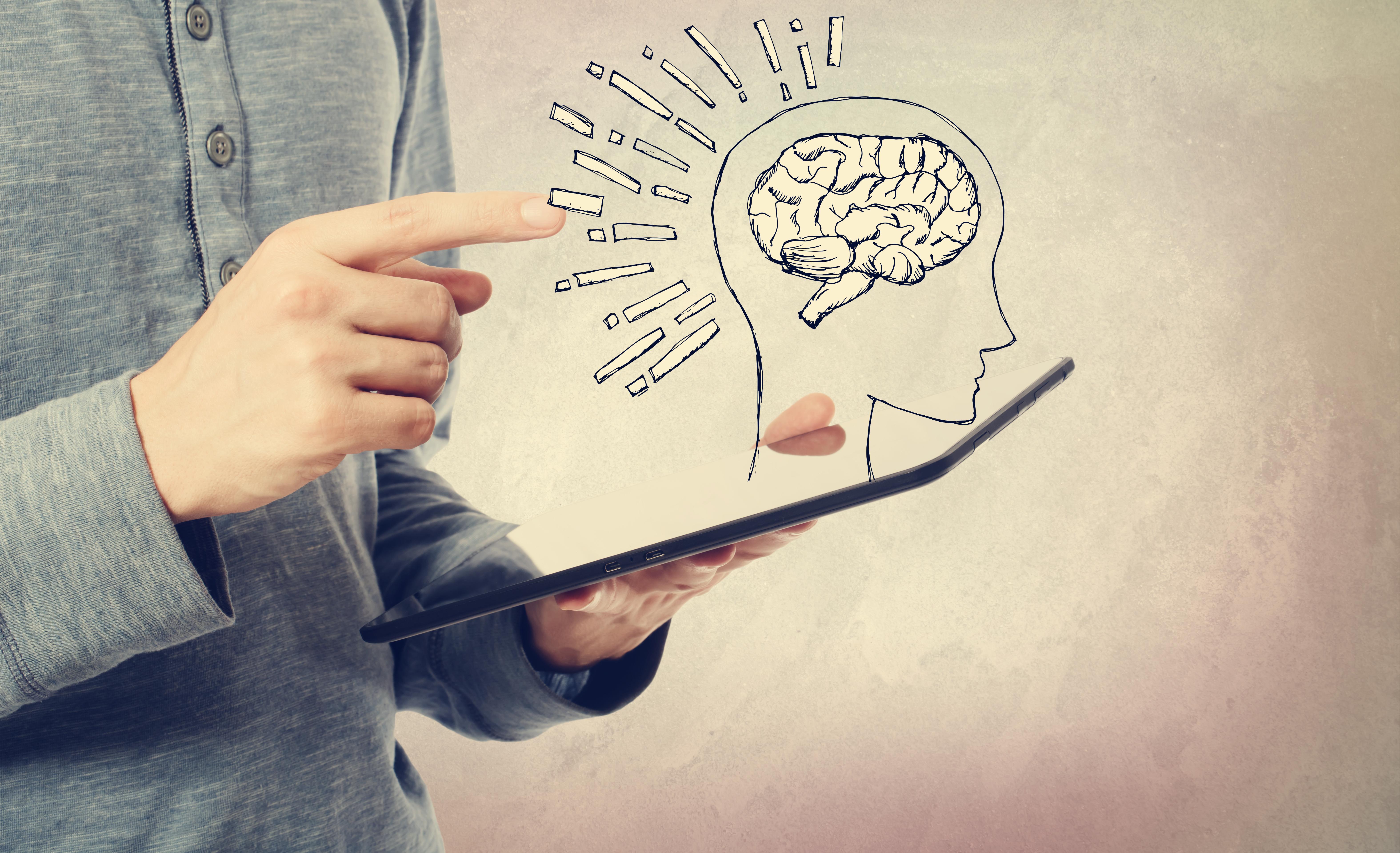 Line drawing of human brain above digital device