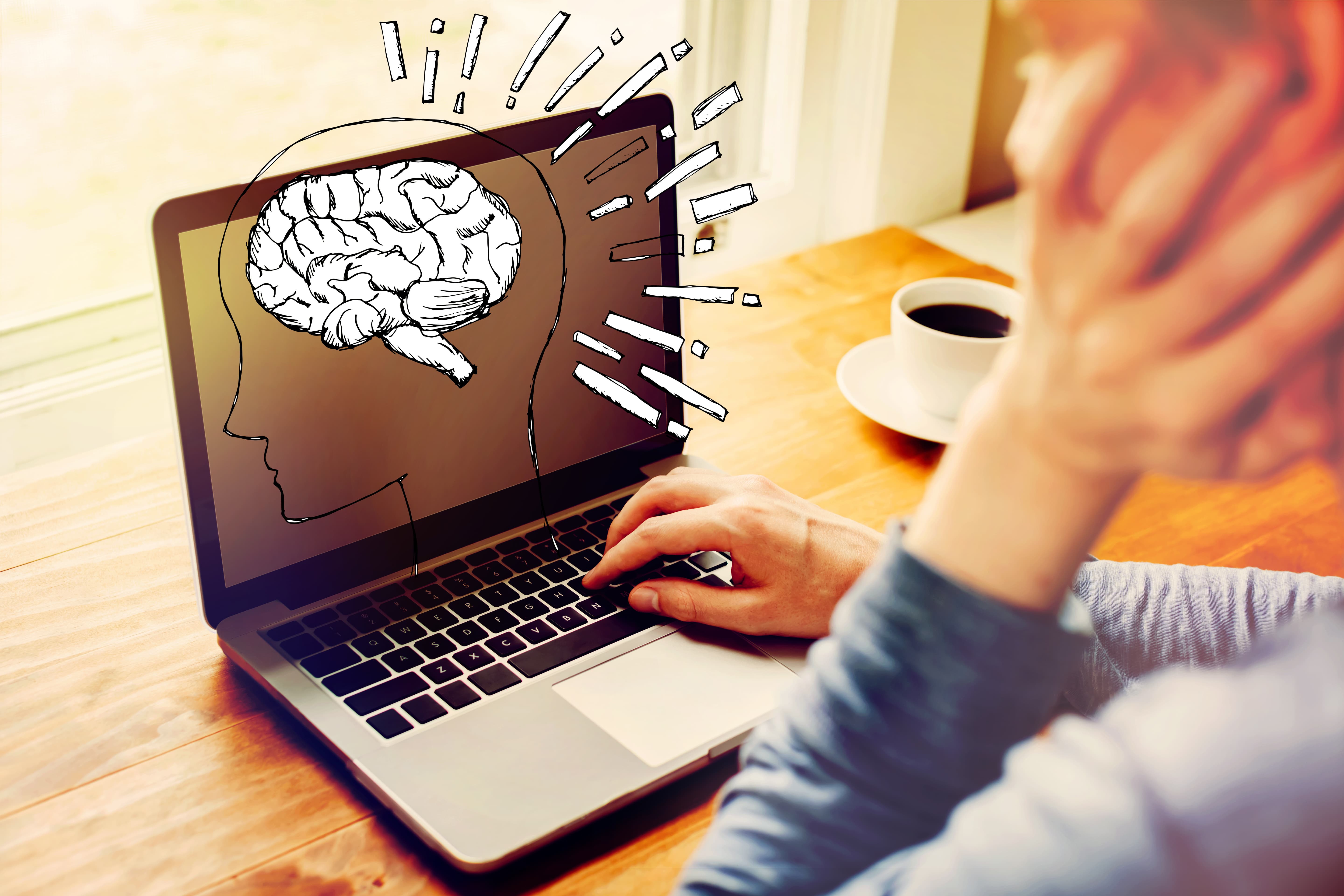 Line drawing of human brain on top of man's laptop