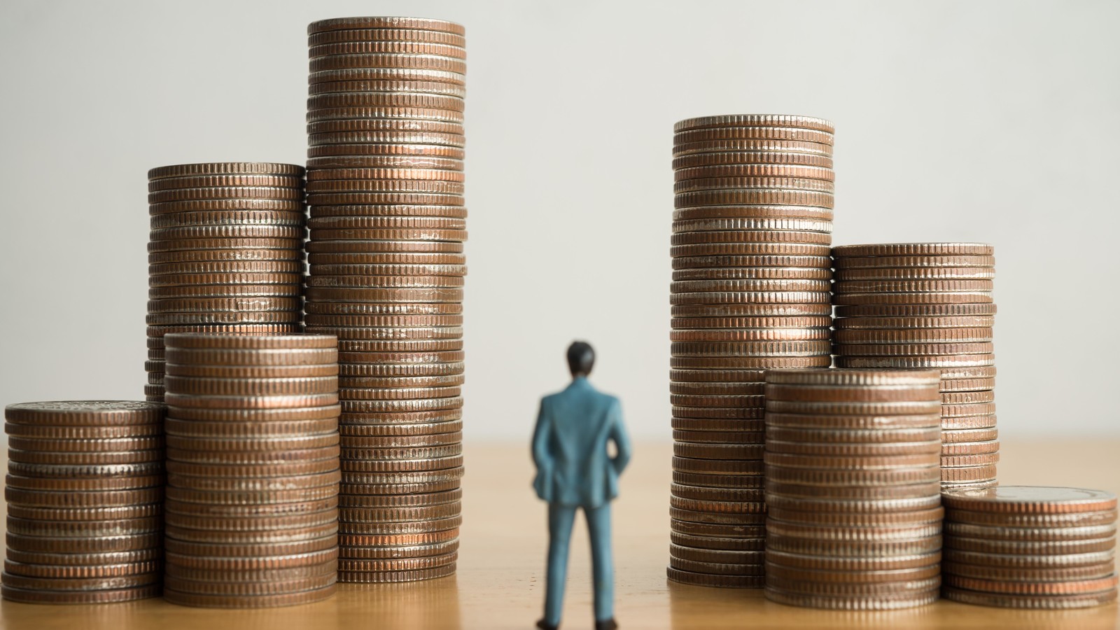 Figurine of man between high piles of coins