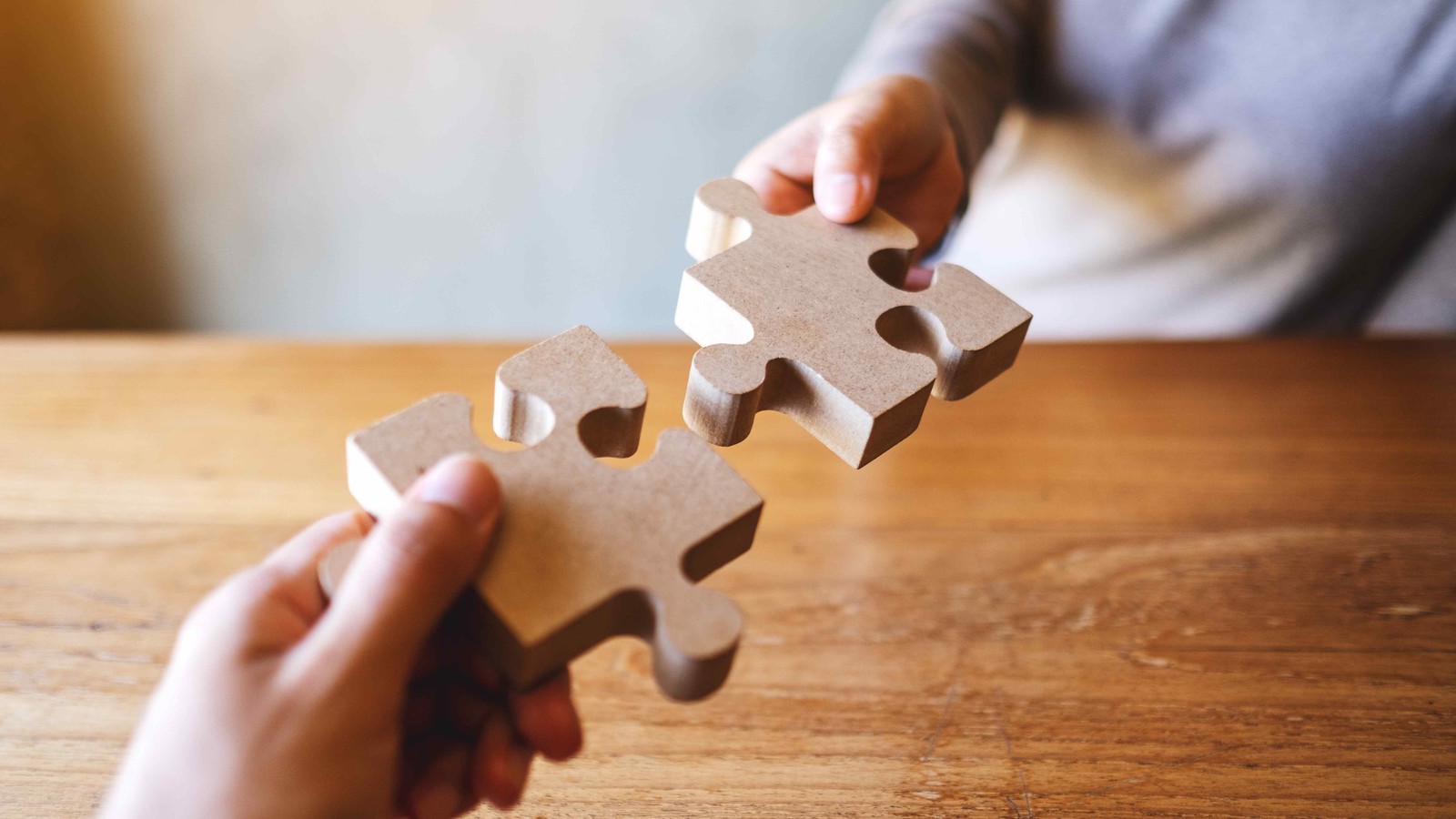 Two people connecting puzzle pieces