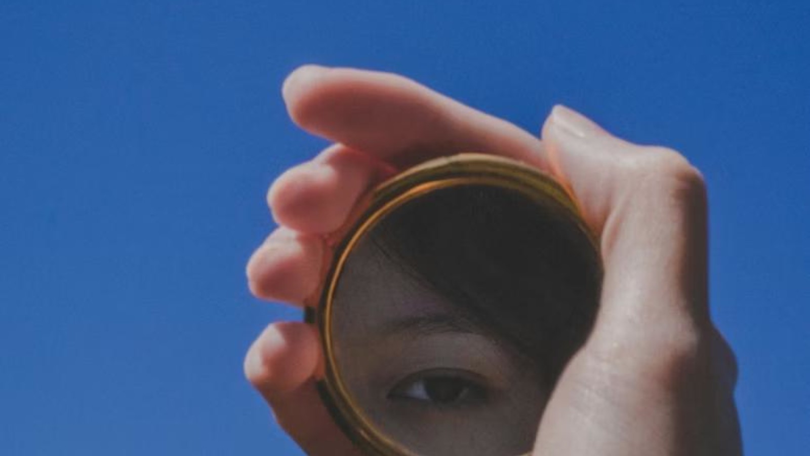 Asian woman holding a small mirror in her hand