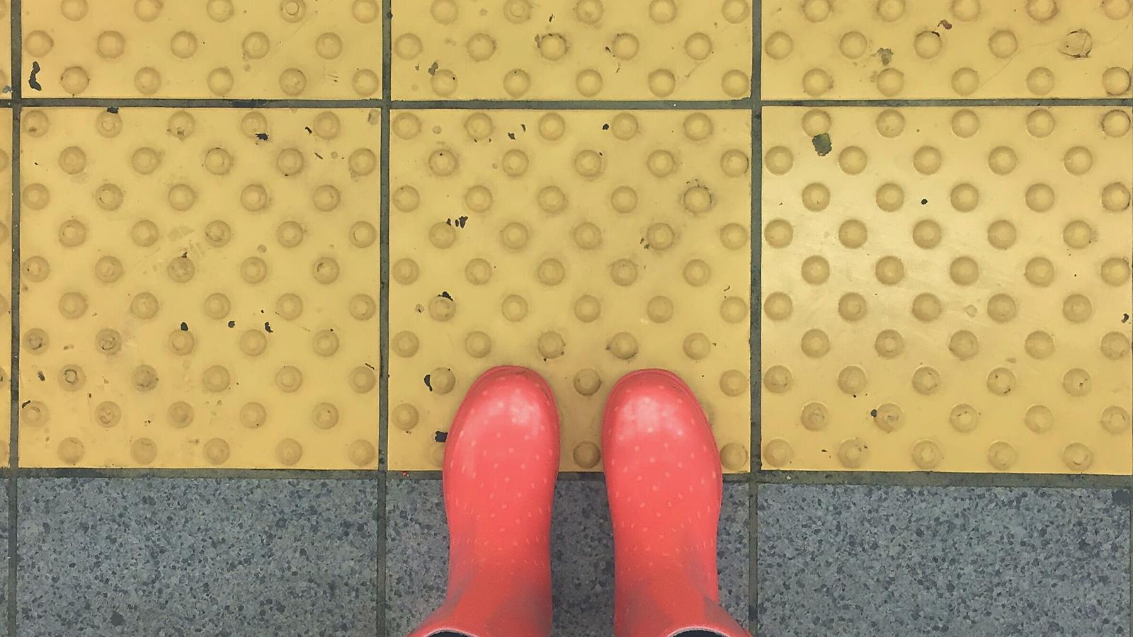 Red rain boots at a crosswalk