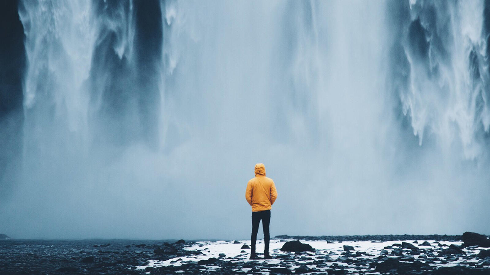 Person standing at the bottom of a waterfall