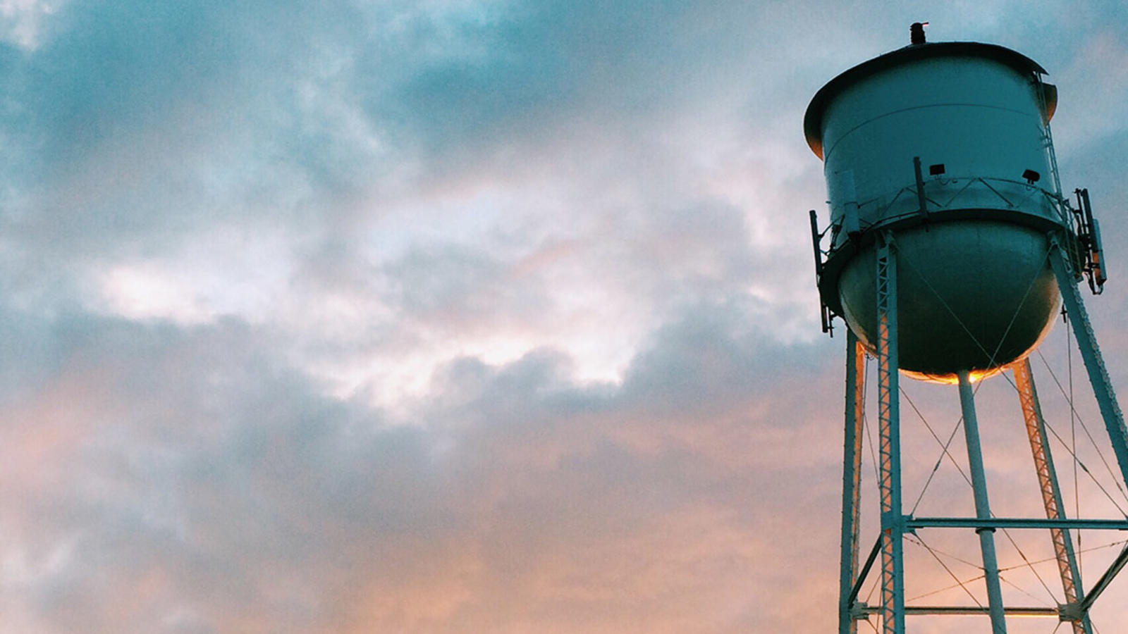 Water tower with sunset behind it.