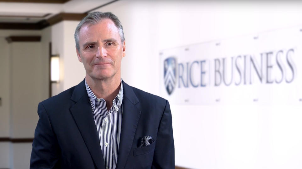 Man standing in front of Rice sign