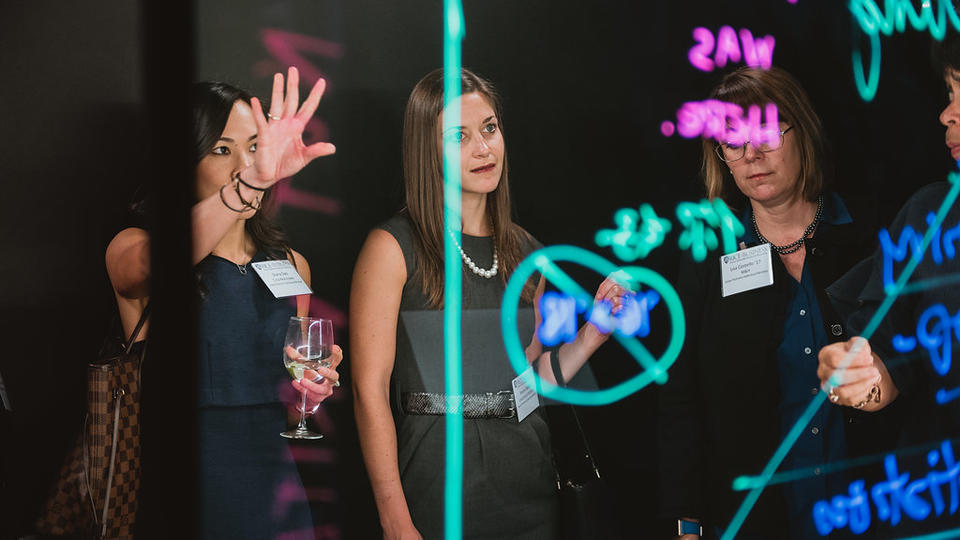 Three female alumni viewing the new recording room at McNair Hall