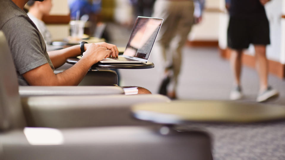 Student on computer in hallway