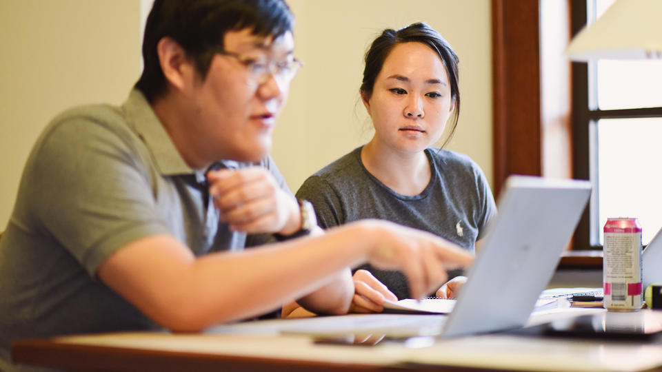 Male and female student working on computer together