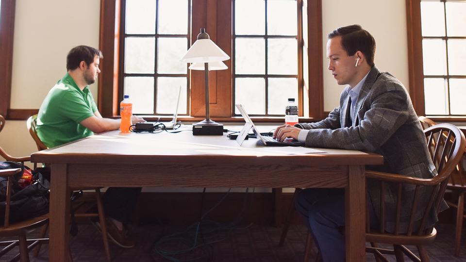 two male students working on table in hallway