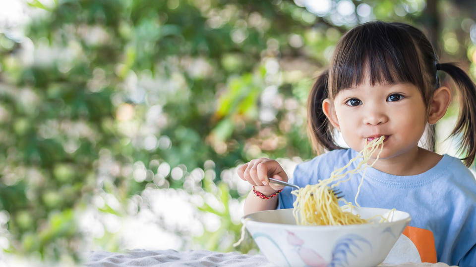 Young Asian girl eating noodles. 