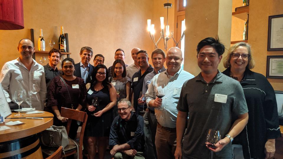 Group of alumni in a wine bar standing in line smiling