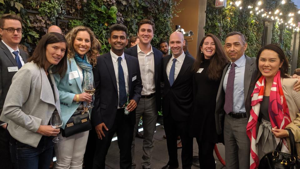 Group of alumni standing at an outdoor bar with drinks