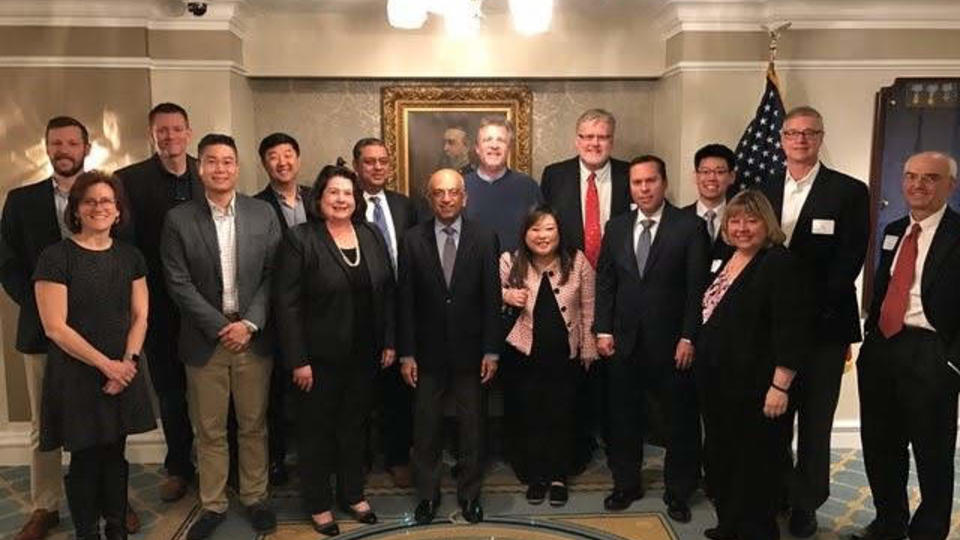 Group of alumni wearing suits standing in a line in a dimly lit room