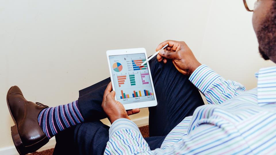 Man looking at iPad with graphs