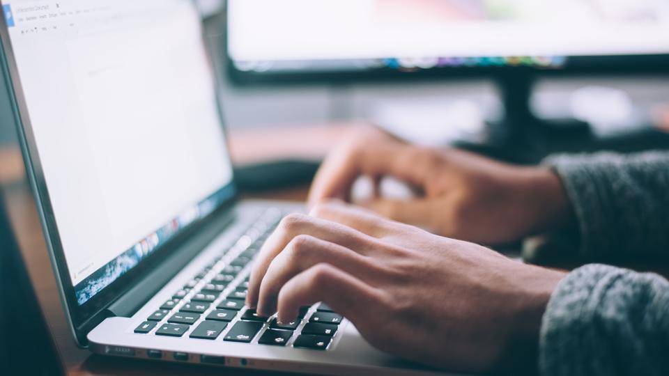 Person's hands typing on MacBook keyboard at a 90 degree angle to viewer