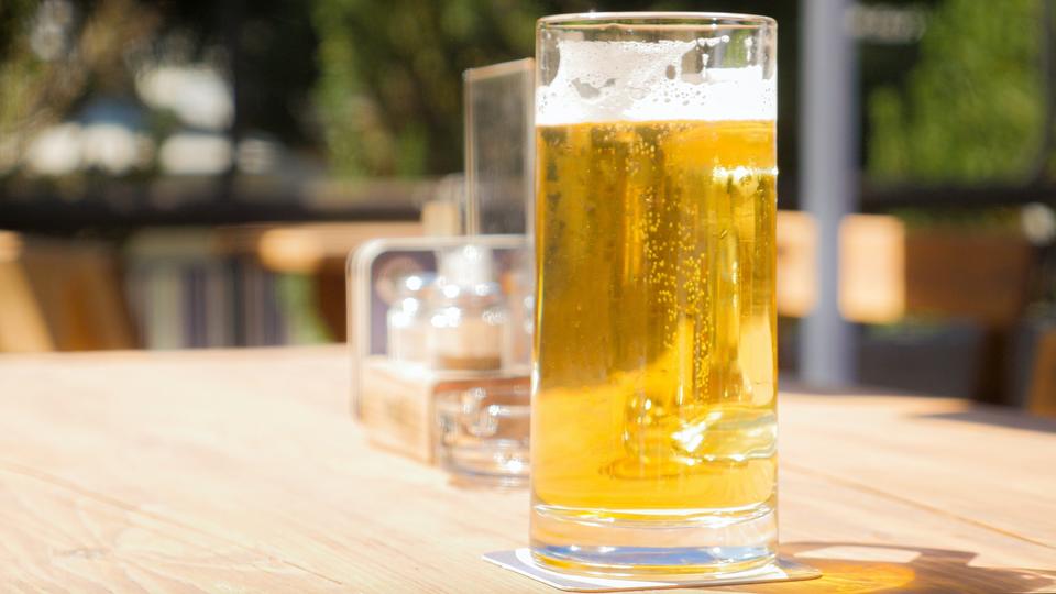 Stein full of pale yellow beer on a wooden table