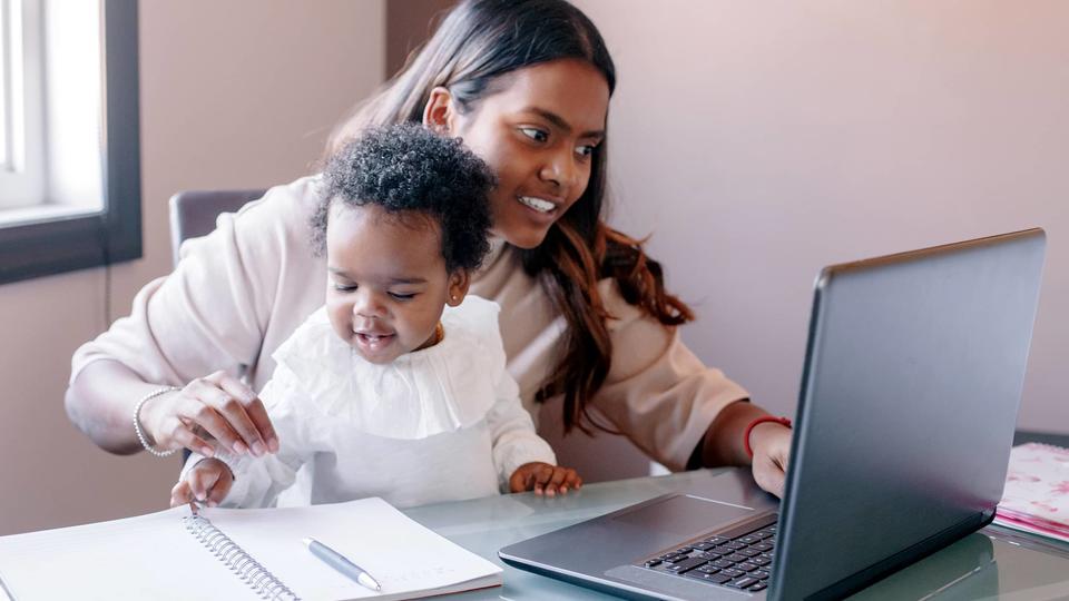 Mother working remotely with a child in her lap