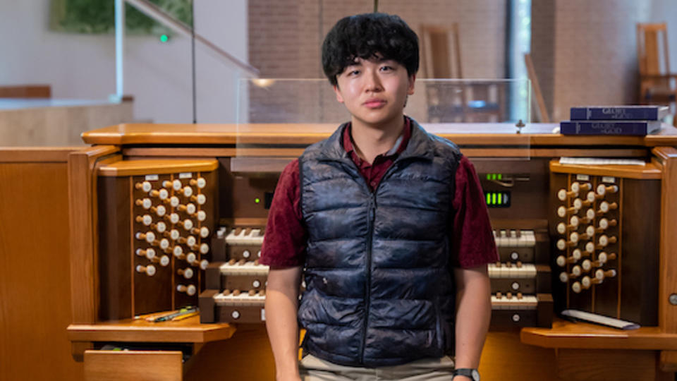 Bruce Xu sits in front of a pipe organ