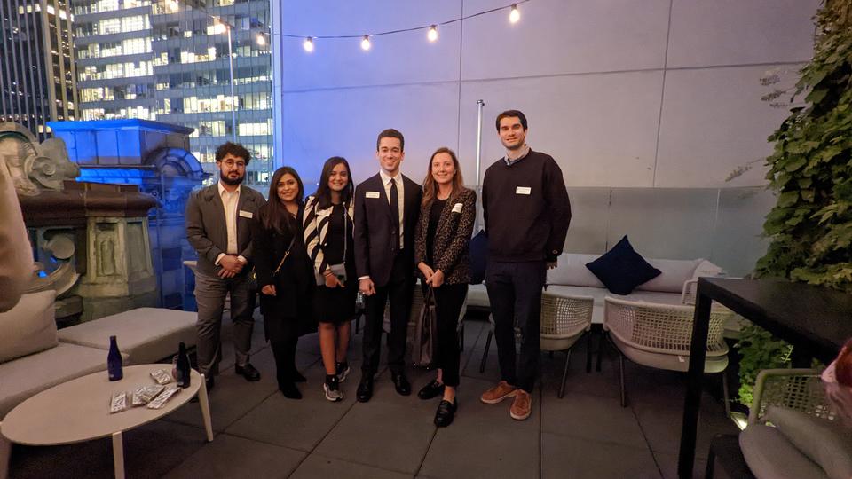 Small group of students and alumni standing at a rooftop bar