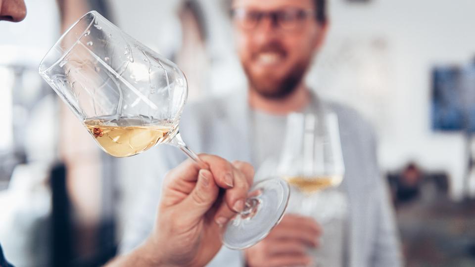 A profile shot of someone tasting a white wine