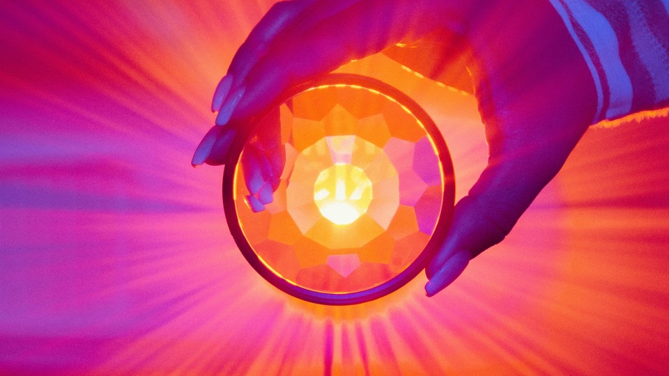 Hand holds a refracted lens in front of colorful light