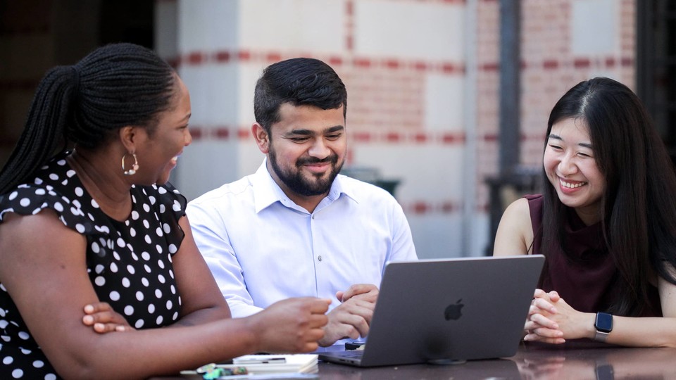 MBA students sitting outside McNair Hall with their laptops