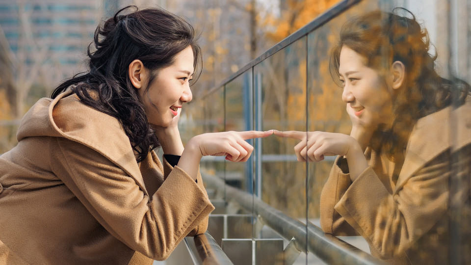 Woman touches reflective glass