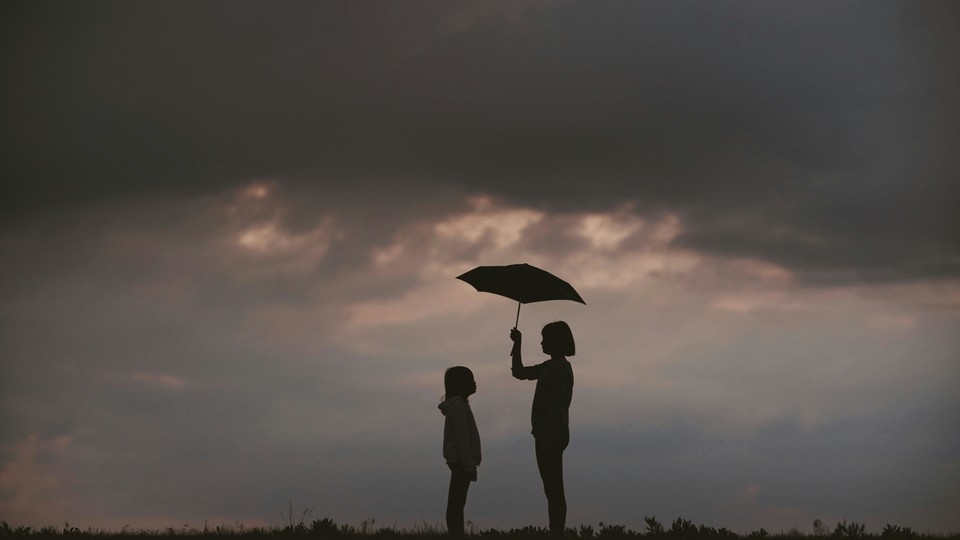One person holding an umbrella over the other