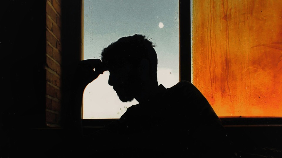 Person sitting in dark room in front of stained window