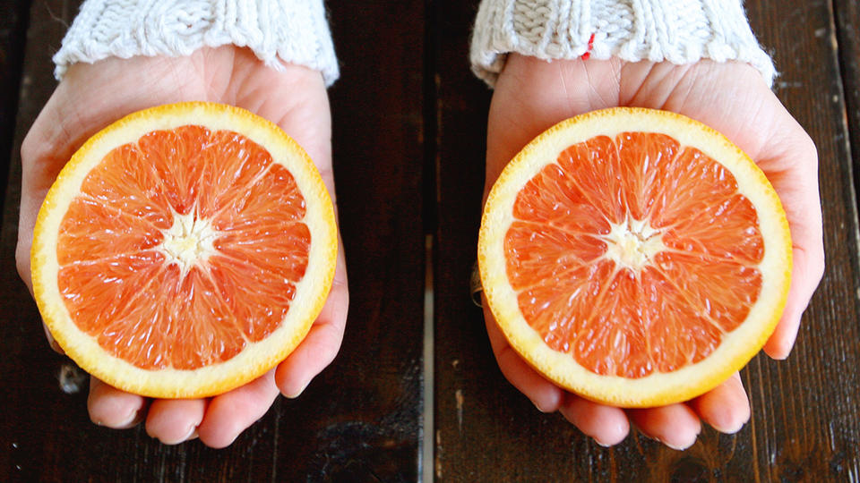 Two halves of oranges being held