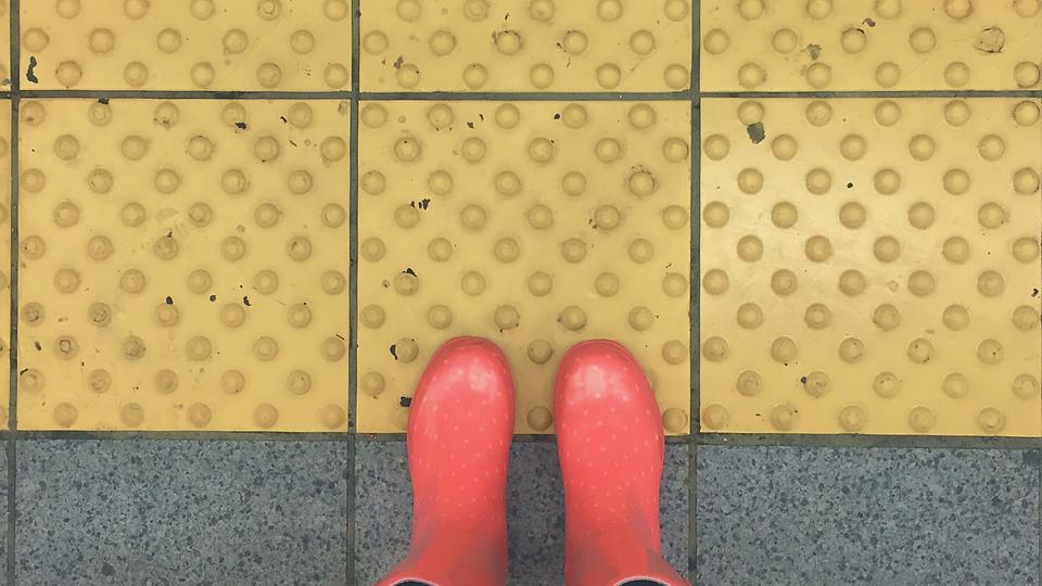 Red rain boots at a crosswalk