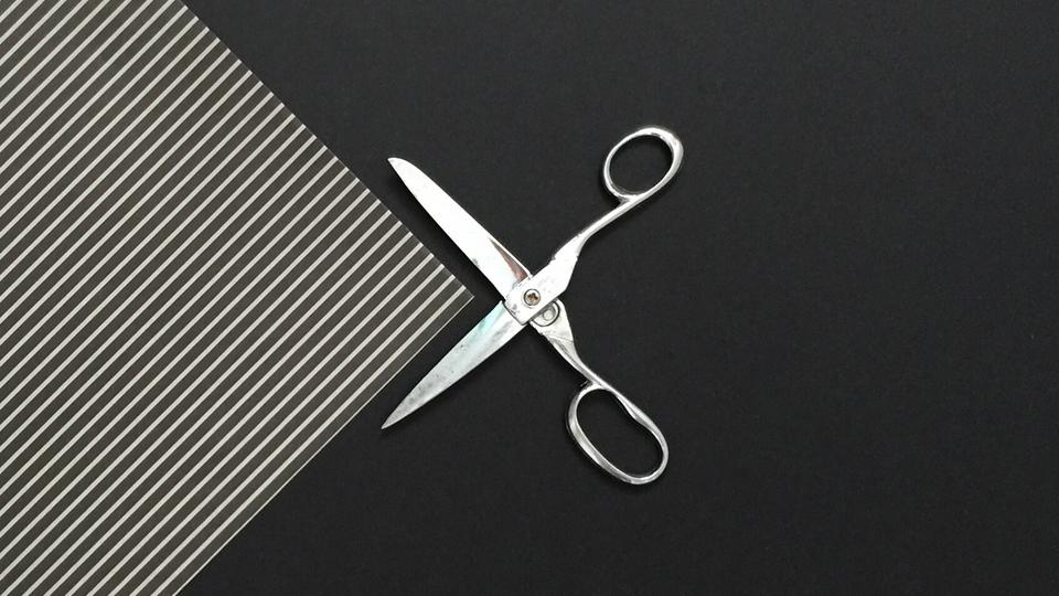 Scissors cutting the corner of a sheet of paper