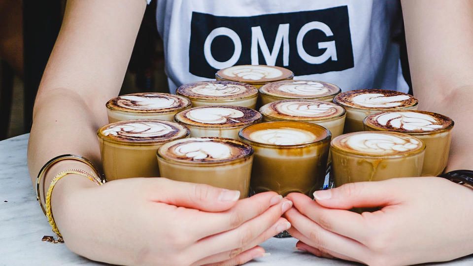 Woman holding several cups of coffee