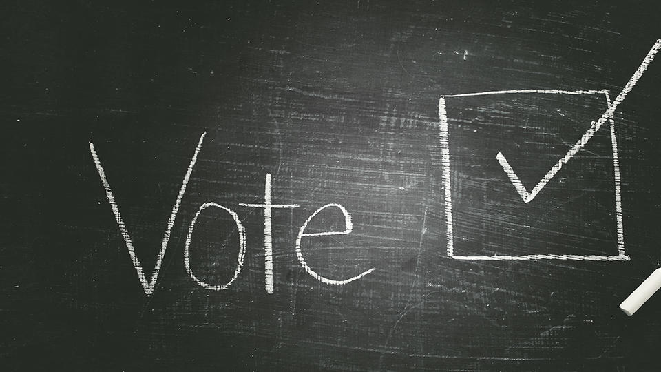 Chalk board that reads "Vote" with a checked box next to it.