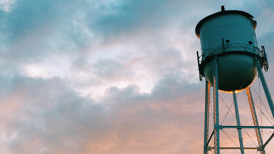 It Takes A Town Water tower with sunset behind it.