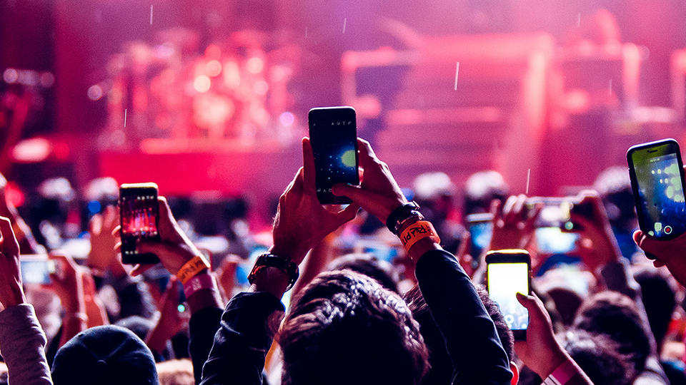 People in a crowd, holding up their phones. 