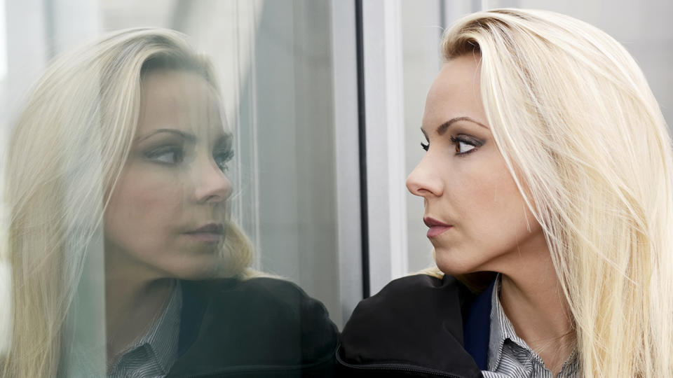 Woman looking at her reflection in a window