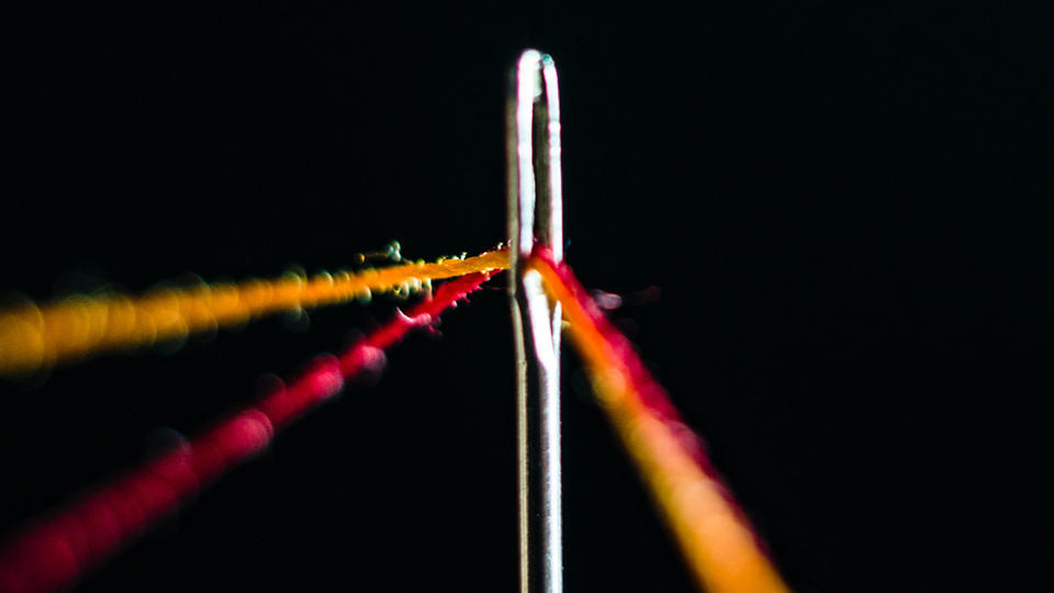 Eye of a needle with thread through it