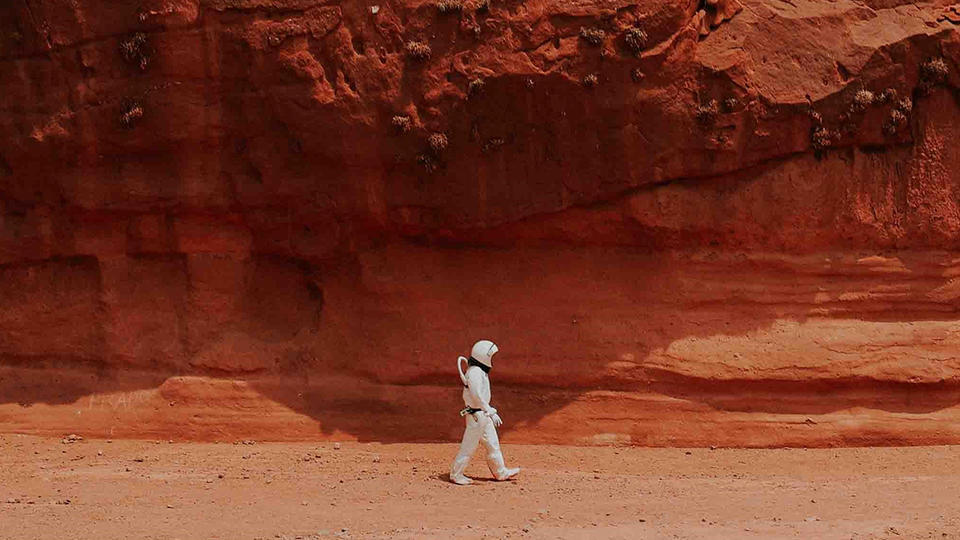 Person in a space suit walking in a desert