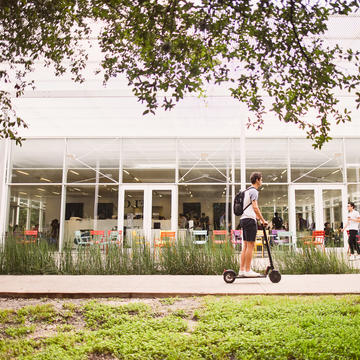 Male riding scooter outside of Brochstein Pavillion