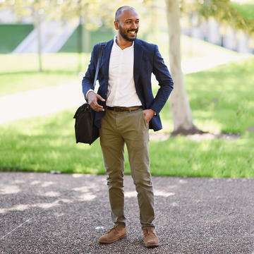 male student with messenger bag standing outside