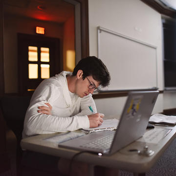 male student studying with laptop in class