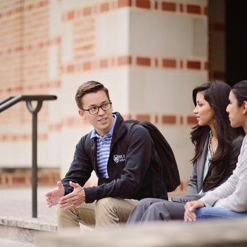 One male and two female students talking on steps outside of McNair Hall